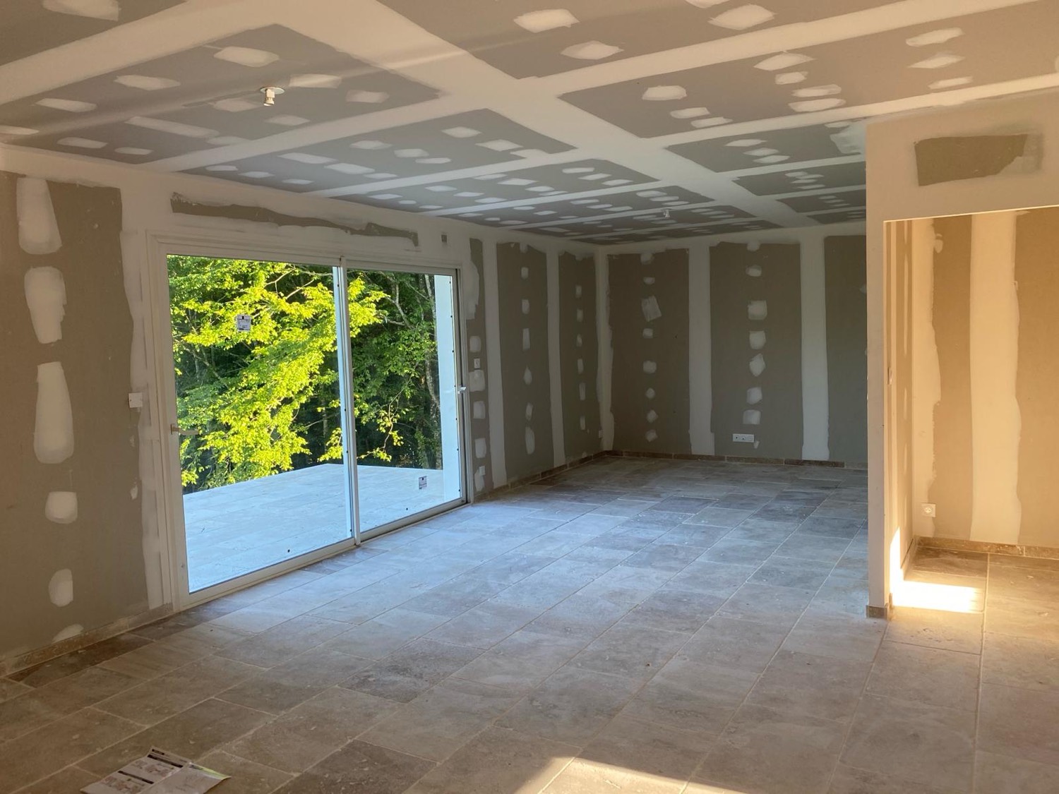 Pièce de vie au stade plâtrerie, baies vitrées, par Neo Construction 24