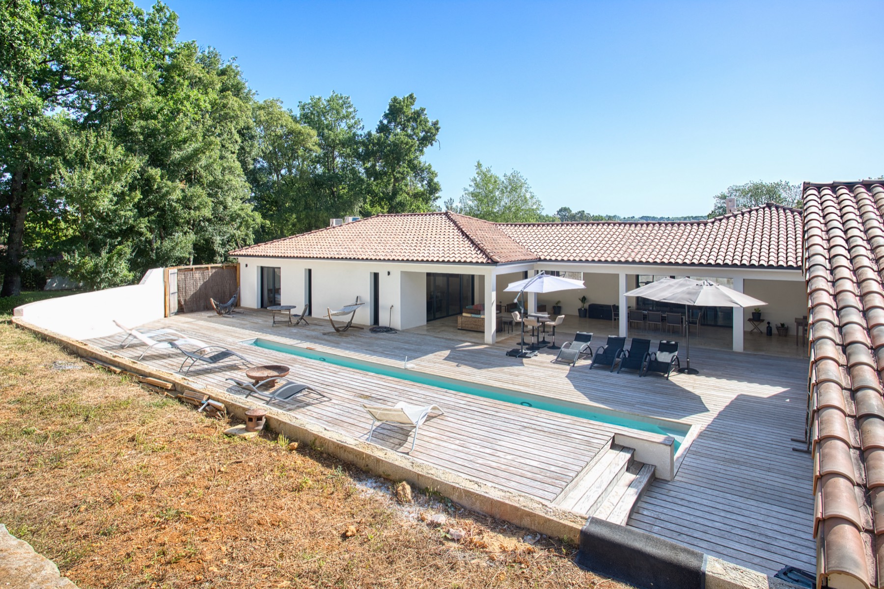 Villa de plain-pied avec couverture tuiles, terrasse bois et piscine, par Neo Construction 24